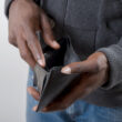 A person thumbing through an empty wallet.